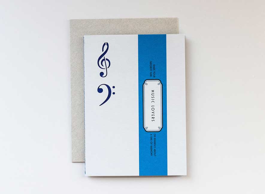 Luxury greeting card in the shape and feel of a playful vinyl record album with electric blue colors and intricate treble and base clef cutouts.