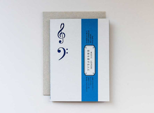 EN-JP| Luxury greeting card in the shape and feel of a playful vinyl record album with electric blue colors and intricate treble and base clef cutouts.