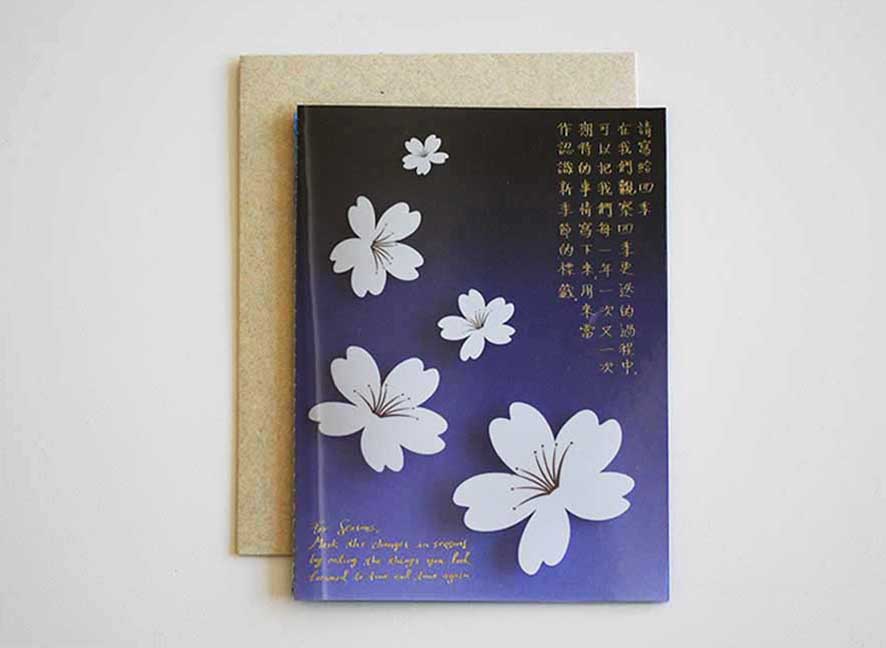 Luxury greeting card with dark violet hue background, cascading white cherry blossom and curated messages delicately printed with gold hot foil stamp.