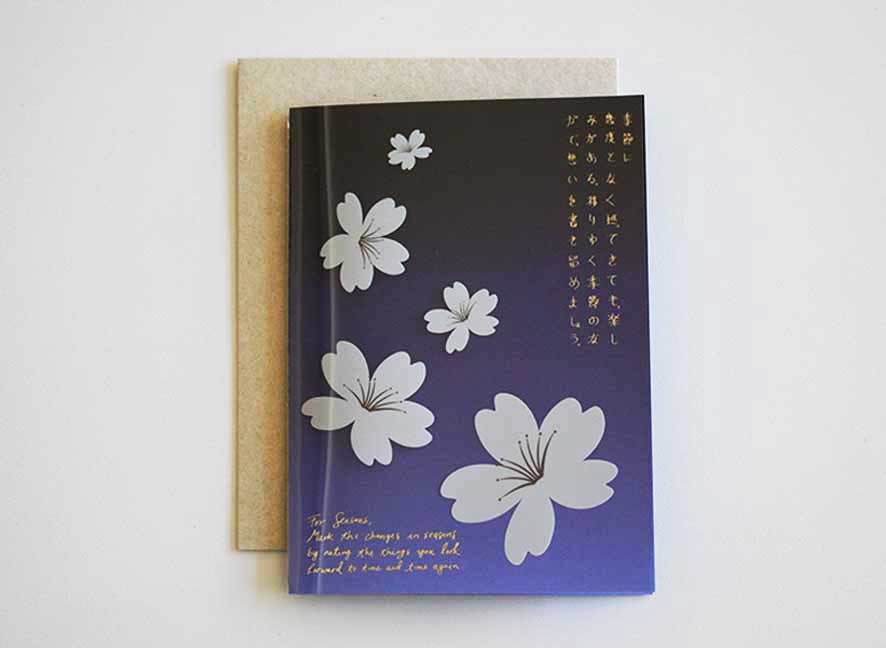 Luxury greeting card with dark violet hue background, cascading white cherry blossom and curated messages delicately printed with gold hot foil stamp.