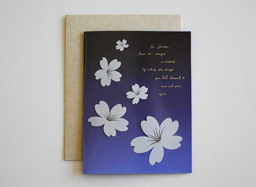 Luxury greeting card with dark violet hue background, cascading white cherry blossom and curated messages delicately printed with gold hot foil stamp.