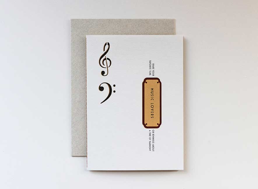 Luxury greeting card. Two-ply card using cream cotton cardstock with intricate treble and base clef cutouts on the exterior. Interior is smooth mustard-yellow paper with maroon accents. English-only version.