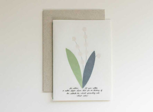 EN| Luxury greeting card with a translucent cover and multi-language messages written on the surface in a cursive style evoking the art of handwriting letters. The interior of a card is an image of a lily of the valley, using different papers and printing styles to give the flower physical texture. English-only version.