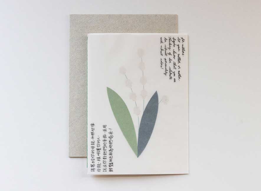 Luxury greeting card with a translucent cover and multi-language messages written on the surface in a cursive style evoking the art of handwriting letters. The interior of a card is an image of a lily of the valley, using different papers and printing styles to give the flower physical texture. English-Chinese version.