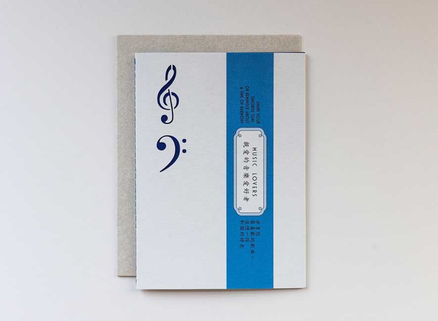  Luxury greeting card in the shape and feel of a playful vinyl record album with electric blue colors and intricate treble and base clef cutouts.