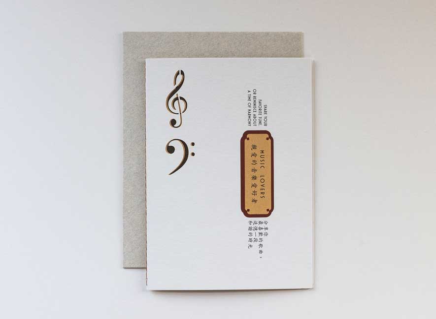  Luxury greeting card. Two-ply card using cream cotton cardstock with intricate treble and base clef cutouts on the exterior. Interior is smooth mustard-yellow paper with maroon accents and messages translated in English and Chinese.